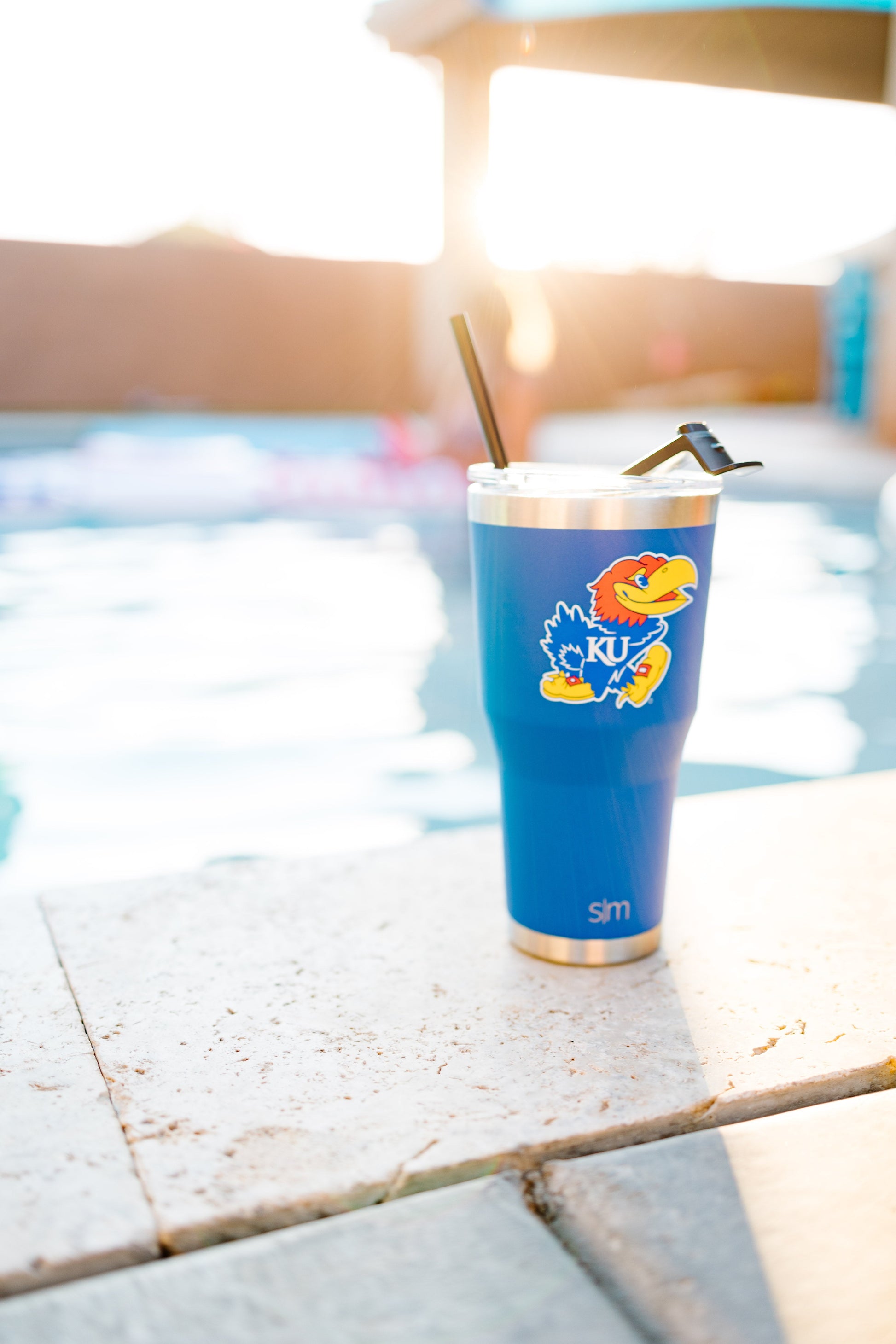Blue insulated tumbler in sharp focus with warm golden sunlight in the background