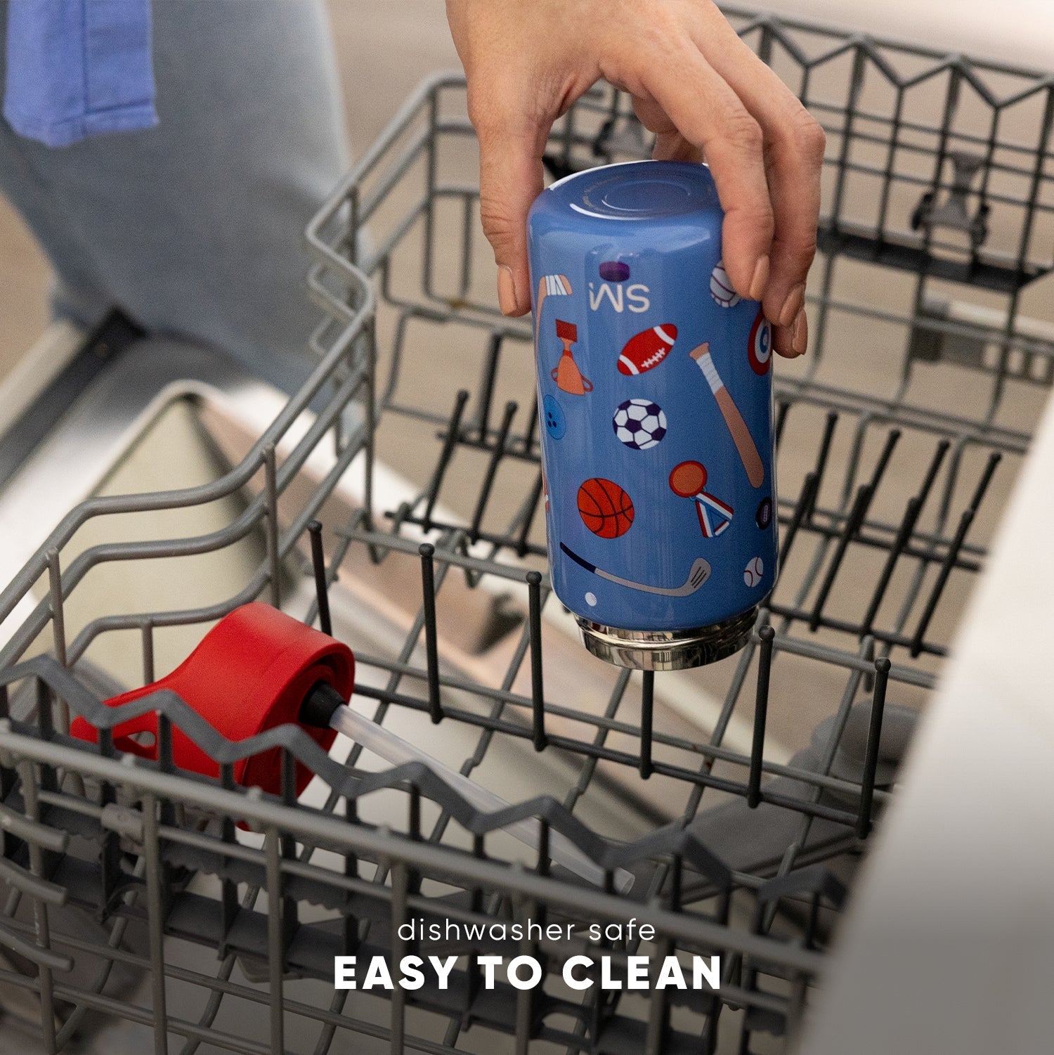 Adult hand holding blue Simple Modern kids water bottle with sports design inside open dishwasher. Text reads "dishwasher safe EASY TO CLEAN."